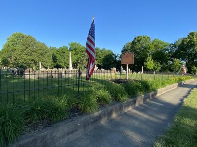 Cemetery historical marker with flags on fence